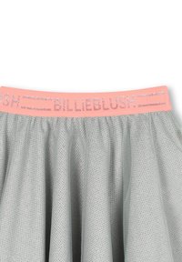 Jupe en maille grise avec une taille en glitter rose portant le texte "BILLIEBLUSH". Le tissu a un design texturé et respirant.