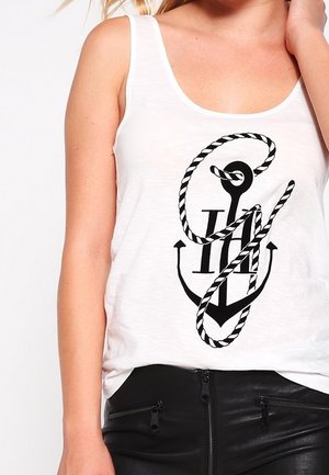 Weißes Tanktop aus leichtem Stoff mit einem schwarzen Anker-Motiv, das Seil-Details und einen lässigen Schnitt aufweist, kombiniert mit schwarzen Lederhosen.