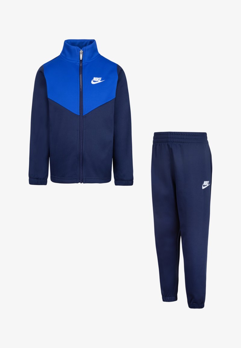 Chándal azul marino que incluye una chaqueta con cremallera y un panel azul con un logo blanco, combinado con pantalones de cintura elástica. Tejido suave y diseño ajustado.