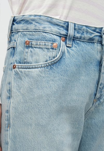 Jean en denim bleu clair avec une conception classique à cinq poches, des rivets métalliques et une finition texturée. Doté d'une coupe droite et de coutures surpiquées.