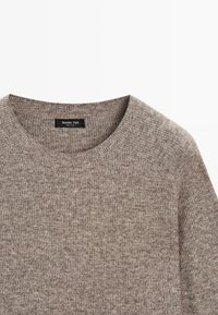 Maglione marrone lavorato a maglia con scollo rotondo e texture a costine. Il tessuto presenta un sottile motivo mélange per maggiore profondità.