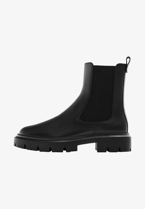 Botte Chelsea en cuir noir avec panneaux latéraux élastiques, semelle épaisse à crampons et languette à l'arrière pour un enfilage facile.
