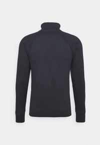 Mörk marinblå tröja med hög krage, långa raglanärmar och ribbade muddar. Slät stickad textur och ren baksida utan utsmyckningar.