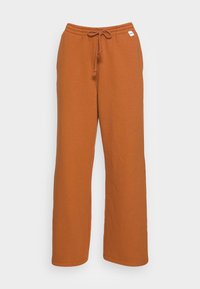 Pomarańczowe spodnie dresowe z miękkiego materiału, o luźnym kroju, z elastycznym paskiem w talii z troczkiem oraz bez widocznych wzorów czy elementów metalowych.