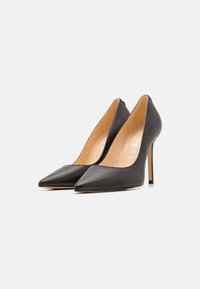 Black leather high heels with a pointed toe design and a stiletto heel. Interior features tan lining with logo detailing.