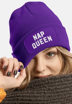Purple knit beanie with a wide patch labeled "NAP QUEEN" in bold white letters. The fabric has a ribbed texture, and it's snug-fitting.
