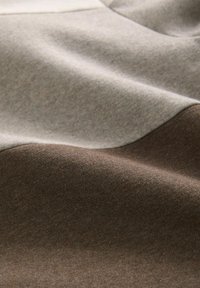 Layered fabric in beige and brown tones, featuring smooth texture with subtle sheen and wavy design elements creating depth.