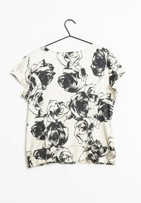 Kortærmet creme top med sort rosenprint, letvægtsstof, løs pasform, rund halsudskæring og foldet kant forneden.