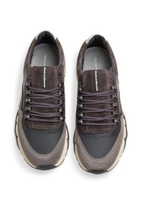 Le sneakers grigio scuro presentano un mix di materiali scamosciati e in rete, con una parte superiore testurizzata, lacci piatti e una suola di colore chiaro.