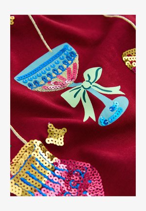 Roter Stoff mit bunten Paillettenverzierungen in Form von Tassen, Schleifen und Mustern. Enthält goldene, pinkfarbene, blaue und grüne Details.