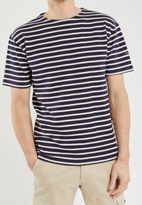 Navy blue and white striped short-sleeve t-shirt, round neck, made of soft fabric, featuring a straight cut and minimal branding on the sleeve.