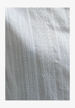 Material alb cu modele brodate intricate, ce prezintă forme geometrice, linii drepte și accente texturate. Aspect ușor și aerisit.