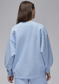 Sudadera azul claro hecha de tela suave, con un corte relajado, hombros caídos y puños acanalados en las mangas y el dobladillo.
