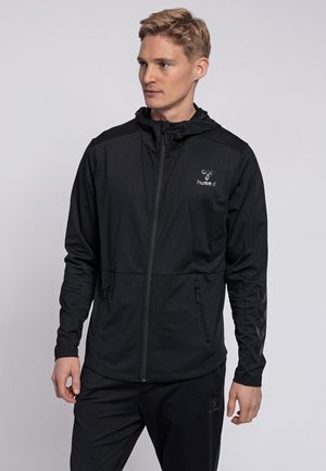 Black zip-up jacket with hood, made of textured fabric. Features logo and chevron pattern accents on sleeves; includes side pockets.