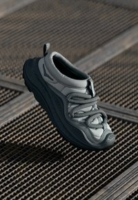 Szare buty sportowe z teksturowaną cholewką, elastycznymi sznurowadłami, amortyzującą podeszwą oraz zaokrąglonym noskiem dla zwiększonego komfortu i wsparcia.