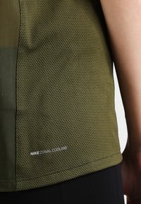 Koszulka Nike Zonal Cooling w kolorze oliwkowym, z oddychającą siateczką i detalem z logo na dole. Krótkie rękawy.