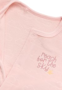 Pijama de bebé rosa hecho de una tela suave, con patrones de nubes y texto bordado "lucha por alcanzar el cielo" con un acento de estrella amarilla.