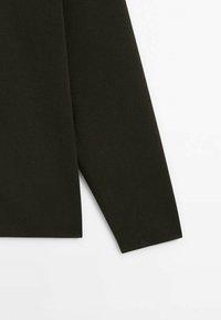 Manche longue d'un pull en maille vert olive foncé avec un ourlet droit sur fond blanc.