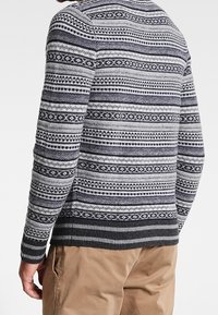 Pull en maille gris avec des motifs géométriques noirs et bleu marine, col rond, ourlet et poignets côtelés. Texture confortable avec une silhouette ajustée.