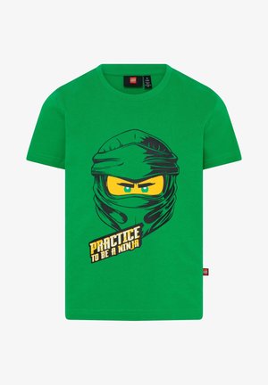 Grøn børne-t-shirt med grafisk illustration af et ninjaansigt og teksten "Øv dig i at være en ninja" på forsiden.