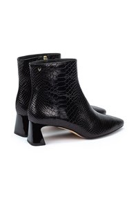 Botines negros de cuero con estampado de serpiente texturizado, con puntera puntiaguda y tacón cuadrado brillante. Cierre con cremallera en el lateral.