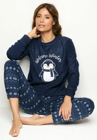 Conjunto de sudadera azul marino que presenta un gráfico de pingüino y el texto "Bienvenido Invierno", con una parte superior de forro polar y pantalones de pijama que muestran un patrón de copos de nieve.