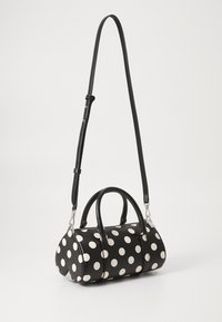 Black polka dot handbag made of smooth material, featuring dual top handles, an adjustable shoulder strap, and silver-tone hardware.