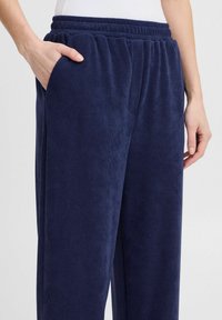Pantalons en velours côtelé bleu marine à coupe décontractée, dotés d'une taille élastique et de poches latérales. Texture lisse avec un motif en côtes.