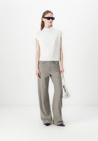 Top blanco de manga corta; pantalones amplios grises; gafas de sol negras; bolso blanco; diseño elegante y contemporáneo; textura suave.