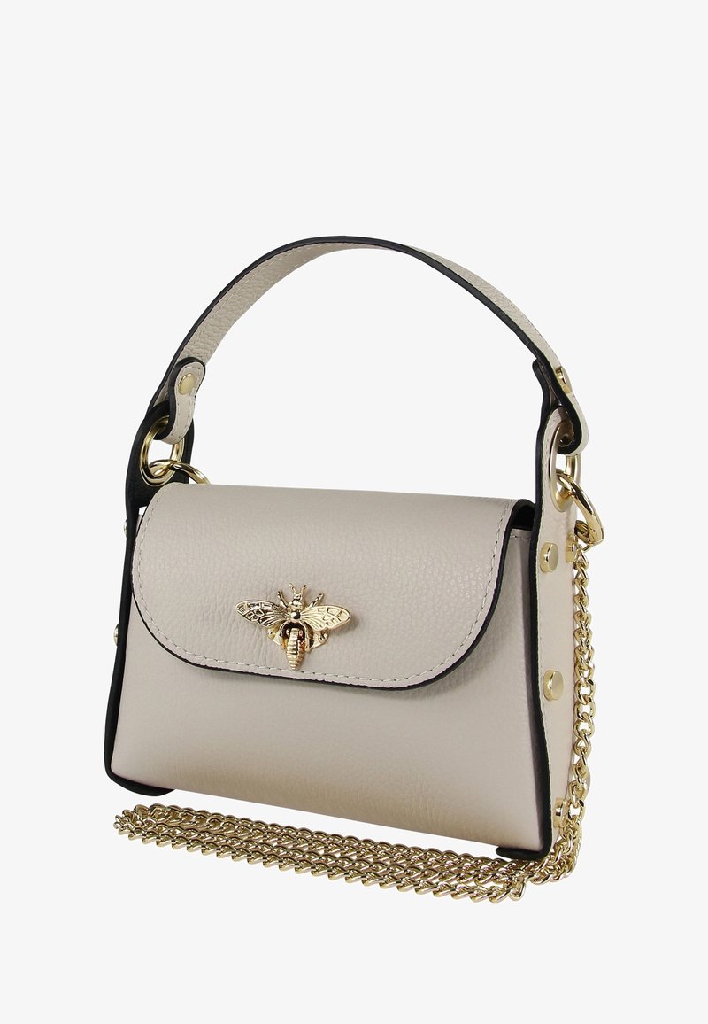 Sac à main en cuir couleur crème avec des accents noirs, arborant un embellissement en forme d'abeille dorée, une chaîne et un design structuré.