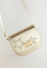 Gul crossbody taske med perforeret stjernedesign, glat metallisk finish, rektangulær form og lås. Justerbar rem inkluderet.