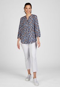 Blue floral blouse with three-quarter sleeves, button front, and round neckline; paired with white cropped pants and white sneakers.