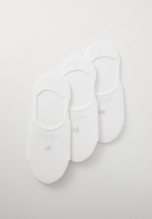 Trois paires de chaussettes blanches sans-show avec un petit logo "ck" gris sur chacune, disposées soigneusement côte à côte sur un fond uni.
