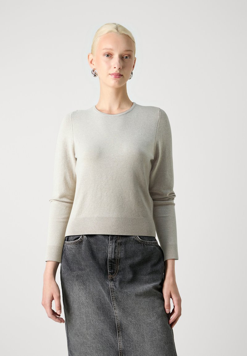 Hellgrauer Rundhalspullover mit langen Ärmeln und geripptem Saum; über einem schwarzen Jeansrock getragen. Glatte Textur, lässige Passform.