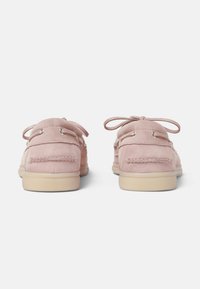 Zapatos de ante rosa con forma redondeada, costuras detalladas, cordones de tela y ojales de metal; suelas de goma de color claro.