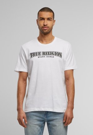 Bijela pamučna majica s okruglim izrezom, kratkim rukavima i crnim grafičkim natpisom "TRUE RELIGION BRAND JEANS" na prednjoj strani.