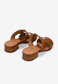 Sandalias de cuero marrón con puntera cerrada y diseño recortado. Cuentan con un tacón bajo y apilado y una plantilla suave para mayor comodidad.