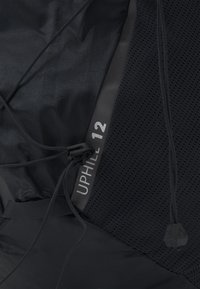 Zaino in tessuto nero con pannello in mesh, dotato di cordino regolabile. Etichetta testuale "UPHILL 12" in argento, che sottolinea il design minimalista.