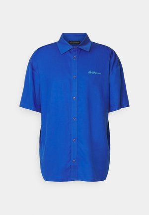 Short-sleeve button-up shirt in bright blue fabric, featuring a smooth texture and a contrasting embroidered logo in turquoise.