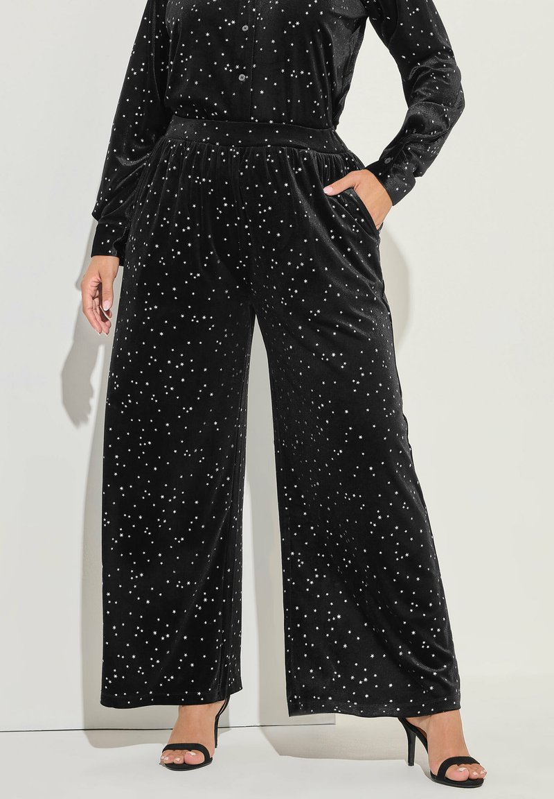 Svarta sammetsbyxor med vida ben som har ett stjärnmönster, elastisk midja, sidofickor och en mjuk textur. Matchas med svarta klackskor.