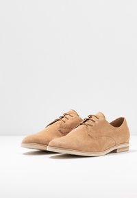 Lichte suède dresschoenen met een gladde textuur, met een klassiek oxford-design, ronde neuzen en dunne veters; platte beige zolen.