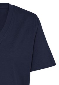 Tissu de T-shirt bleu marine à manches courtes et col en V avec des coutures visibles sur la manche et le col sur fond blanc.