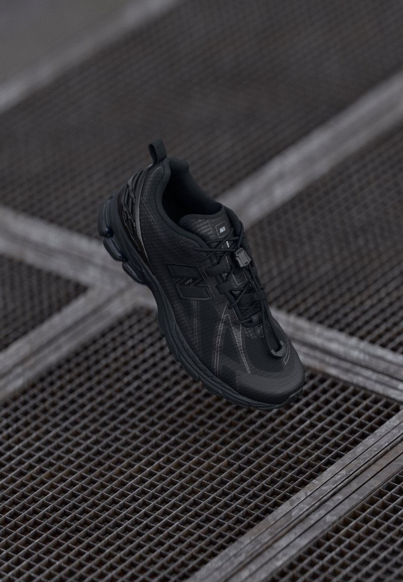 Scarpa da ginnastica nera con tomaia texture, sole ammortizzato e lacci piatti. Presenta dettagli del logo e un'etichetta sul tallone per una facile calzata.