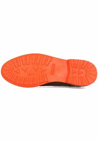 Suela de zapato con un diseño resistente y patrones de banda de rodadura profundos en goma naranja, que contrasta con una parte superior oscura.