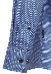 Blaues Hemd mit Knopfleiste und kleinem weißen Punktmuster, mit einem Manschette mit zwei dunklen Knöpfen und einer gewebten Stofftextur.