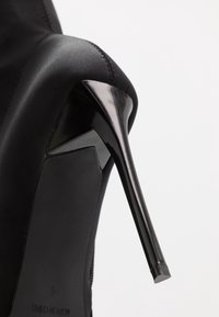 Scarpa con tacco alto nera con una parte superiore in satin elegante, punta affusolata e un tacco a stiletto sottile e lucido per una silhouette elegante.