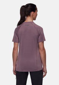 Kortärmad, lila sporttröja gjord av ett mjukt, lätt tyg; har rund halsringning och kontrasterande sömmar.