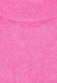 Maglione in maglia rosa peloso con superficie testurizzata e scollatura a coste. Il tessuto appare morbido e caldo, con un colore uniforme.