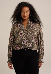 Blusa floreale con una base verde scuro e motivi beige, viola e rosa. Maniche lunghe con polsini arricciati e scollatura a V.