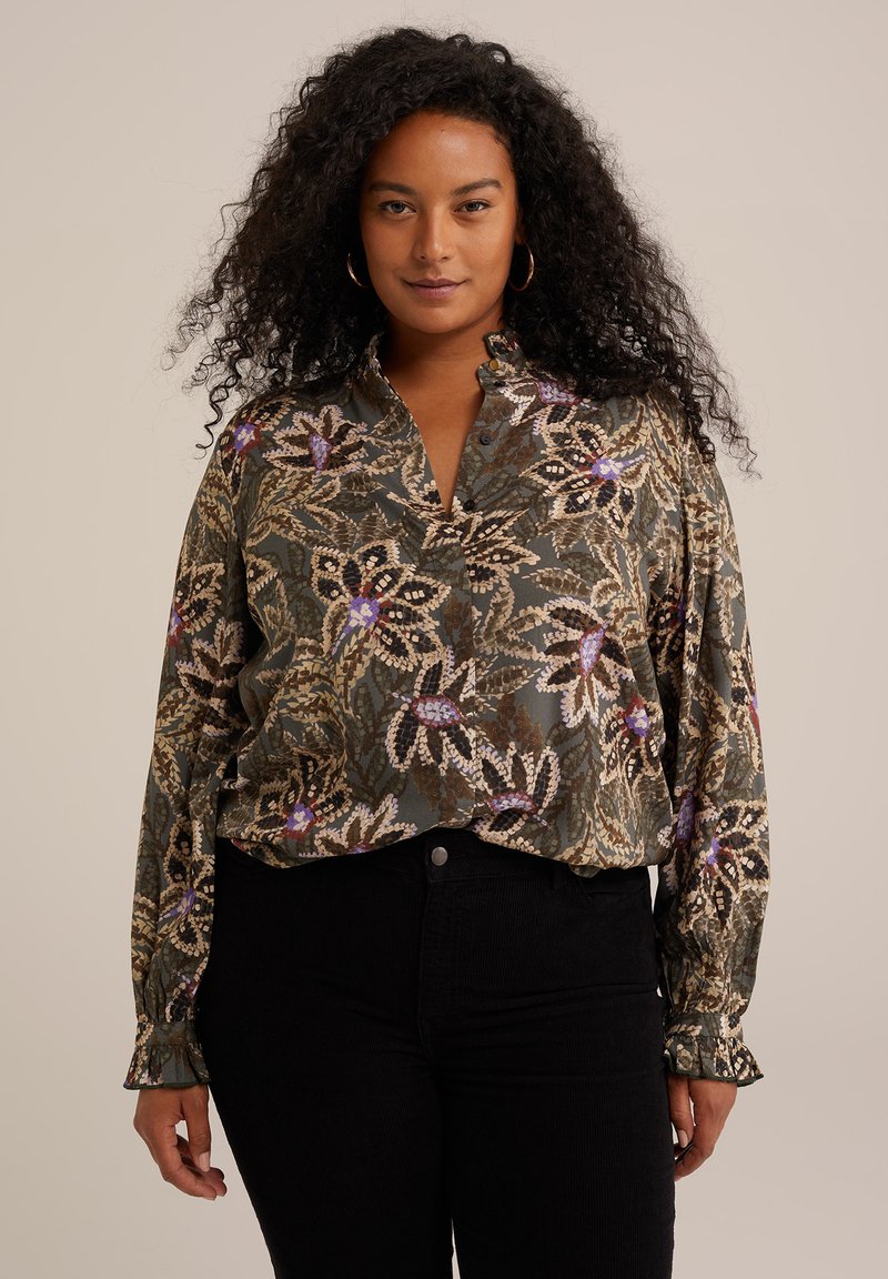 Blusa floreale con una base verde scuro e motivi beige, viola e rosa. Maniche lunghe con polsini arricciati e scollatura a V.
